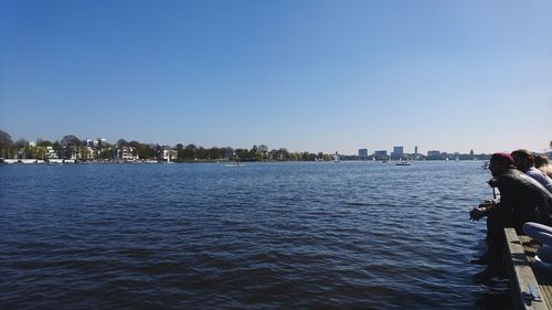 Rear view of man on river against cityscape