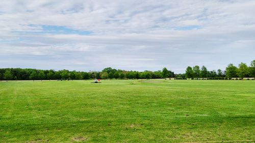 Scenic view of golf course on field against sky