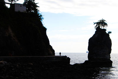 Statue on rock by sea against sky