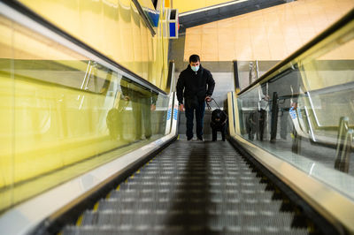 Blind man walking on escalator with guide dog