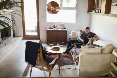 Father and son using digital tablet on sofa at home