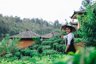 Portrait of farmer carrying wicker basket while working at farm