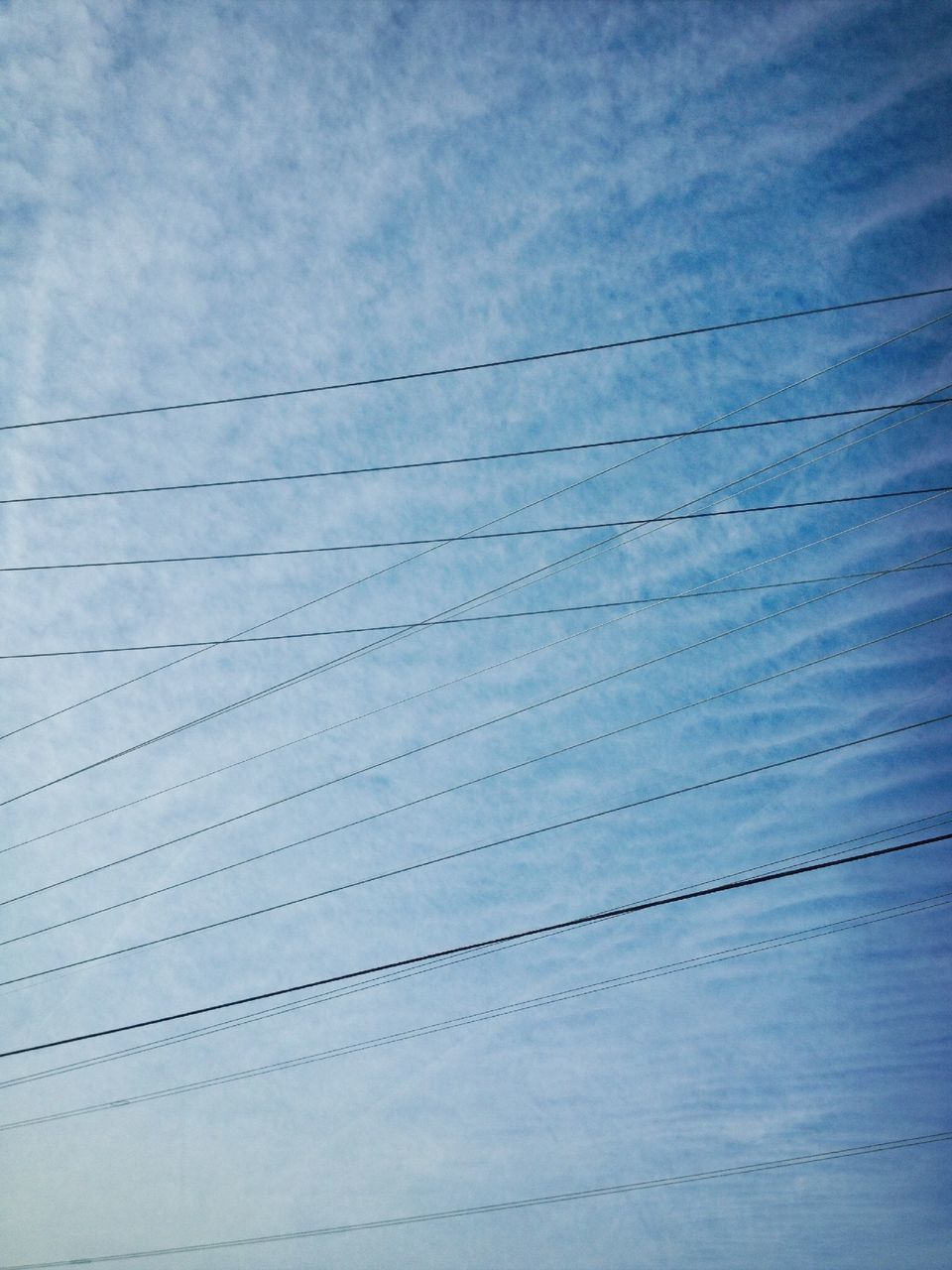 sky, connection, built structure, low angle view, cloud - sky, architecture, bridge - man made structure, cable, blue, day, outdoors, no people, pattern, cloud, power line, nature, transportation, cloudy, engineering, tranquility