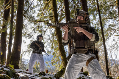 Low angle view of man standing against trees in forest