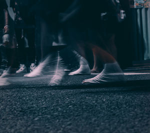 Low section of people walking on road in city