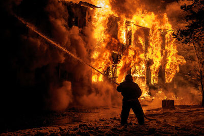 Firefighter spraying water on burning fire at night