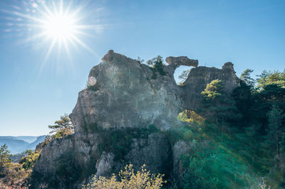 Low angle view of rock formation against sky on sunny day