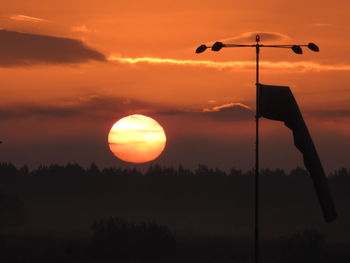 Silhouette street light against orange sky