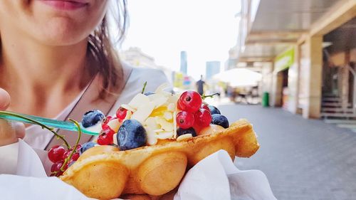 Midsection of woman having food in city