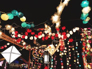 LOW ANGLE VIEW OF ILLUMINATED LIGHT BULBS AGAINST SKY AT NIGHT