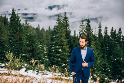 Young man standing against trees in forest