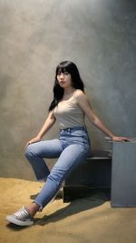 Portrait of woman sitting against wall