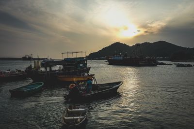 Boats moored on sea against sky during sunset