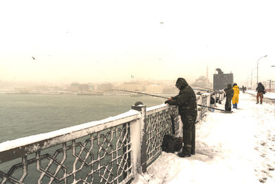 People looking at cityscape against clear sky during winter