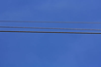 Low angle view of cables against clear blue sky