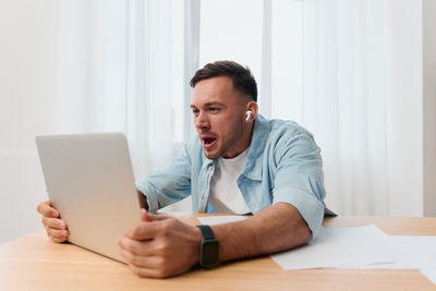 Man using mobile phone while sitting on table