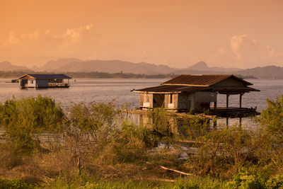 Houses in river against sky during sunset