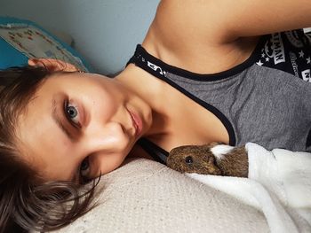 Portrait of young woman with cat relaxing on bed at home