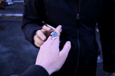 Cropped hand giving marijuana joint to friend on road