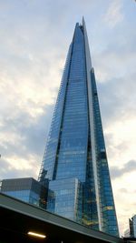 Low angle view of modern building against cloudy sky