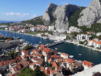 Aerial view of townscape by sea against sky