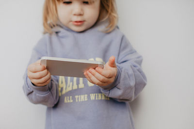 Portrait of young woman using mobile phone against wall