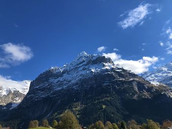 Low angle view of snowcapped mountains against blue sky