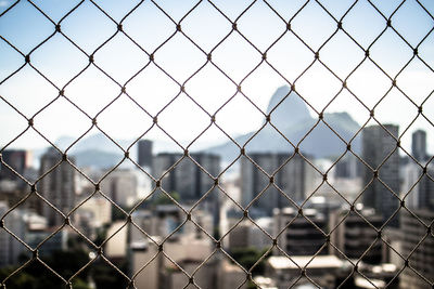 Full frame shot of chainlink fence against cityscape