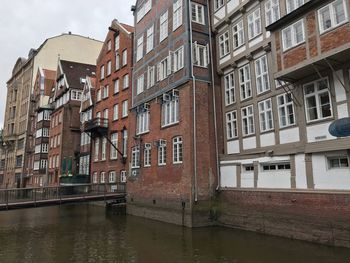 Low angle view of buildings by river against sky