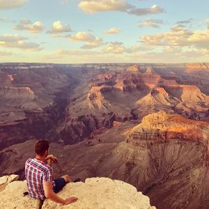 Rear view of man looking at mountains against sky