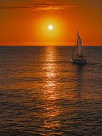 Sailboat sailing on sea against sky during sunset