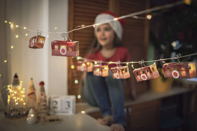 Cute girl looking away while sitting by christmas decoration