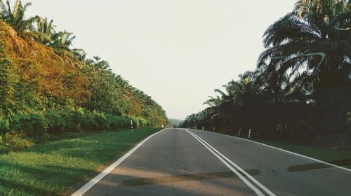 Road amidst trees against clear sky