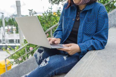 Midsection of woman using laptop while sitting on steps