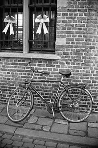 Bicycle parked against brick wall