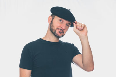 Portrait of man wearing hat standing against white background