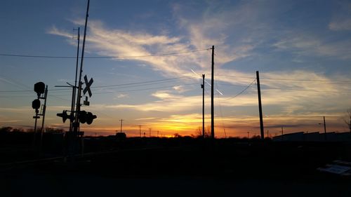 Silhouette of street lights against sky during sunset