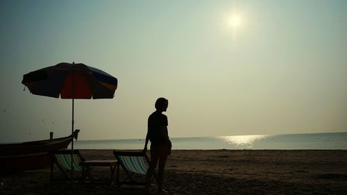 Silhouette woman at beach against clear sky during sunset