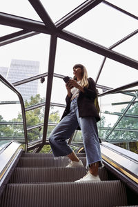 Woman with smart phone standing on escalator