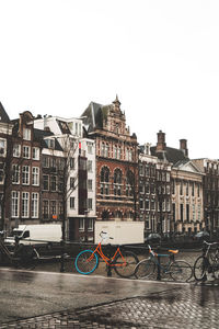 Bicycles on street by buildings against sky