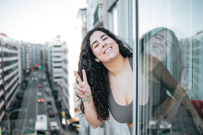 Portrait of smiling woman gesturing looking out of window