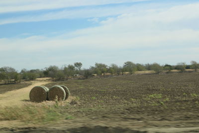 Hay bales on field against sky