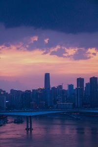 Modern buildings in city against sky during sunset