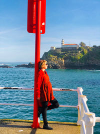 Rear view of woman standing by sea against sky