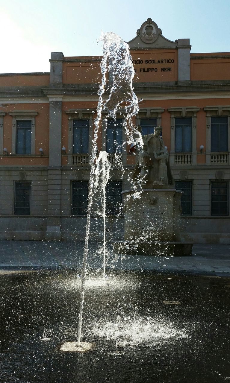 building exterior, fountain, architecture, built structure, motion, water, splashing, spraying, drop, wet, long exposure, low angle view, statue, sculpture, clear sky, city, outdoors, building, day, window