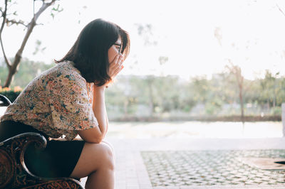 Side view of young woman sitting outdoors