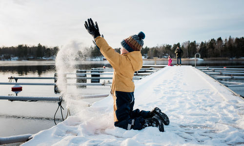 Boy throwing snow up in the air whilst playing by the water in sweden