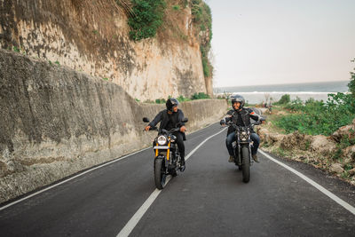 Rear view of man riding motorcycle on road