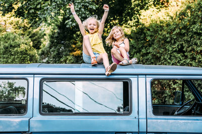 Two girls happy and excited sitting on top of vintage car