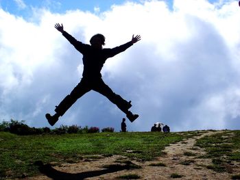 Low angle view of man jumping on field against sky